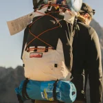 کوهنورد با کوله بزرگ در مسیر کوهستان برای انتخاب حجم مناسب کوله
