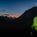 کوهنورد مجهز به هدلامپ در مسیر کوهستان هنگام غروب