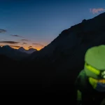 کوهنورد مجهز به هدلایت در ارتفاعات هنگام غروب